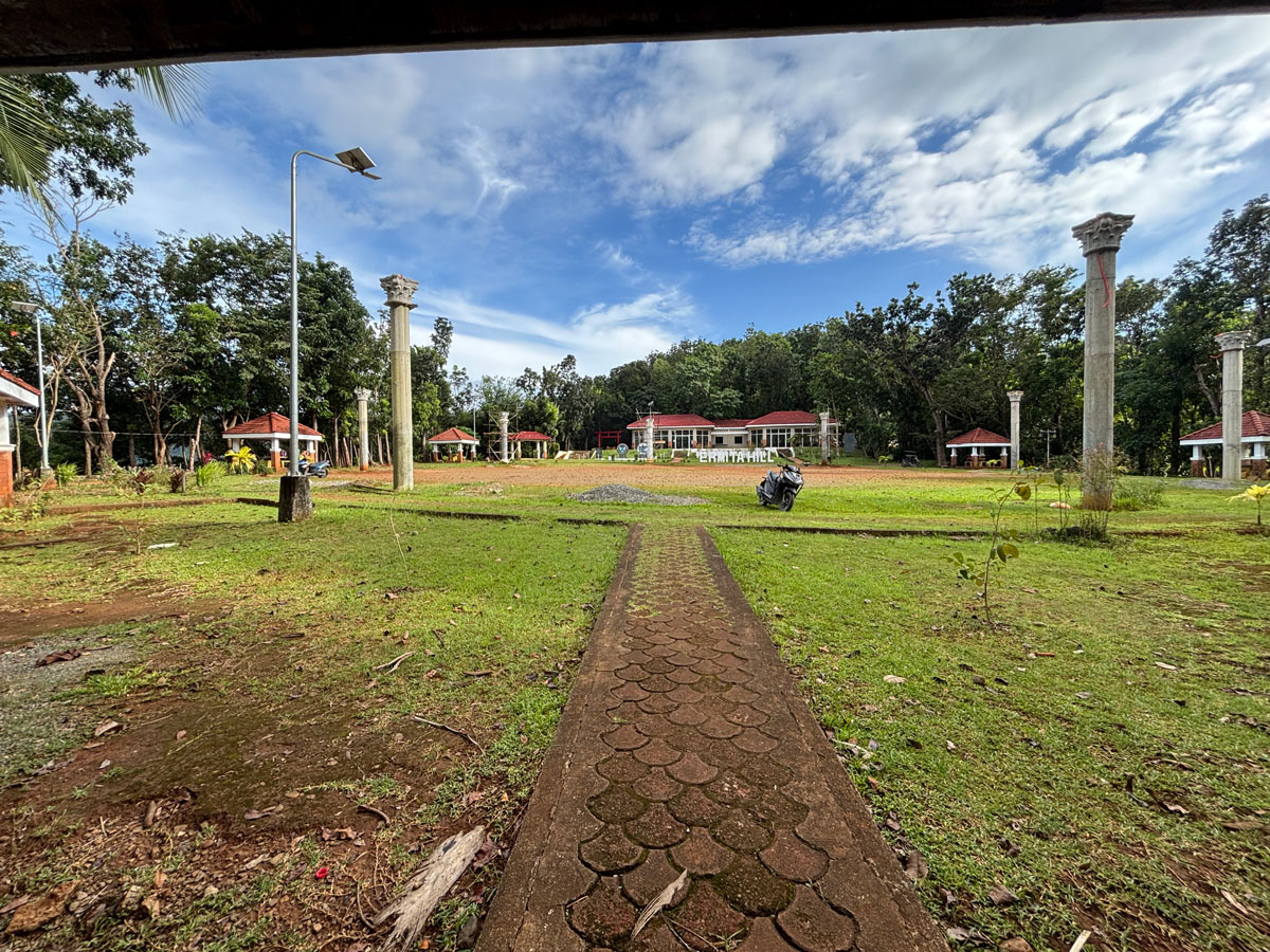 Open field at Ermita Hill with scattered pillars, cottages, and a building in the background under a bright sky