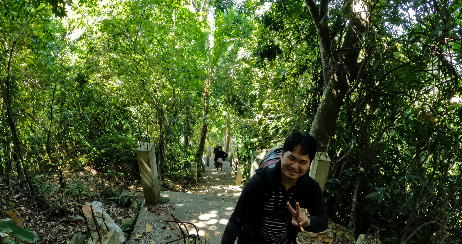 Traveler hiking the forest trail with concrete steps leading to Bantay Lobbot viewpoint in Dipaculao, Aurora, surrounded by lush tropical trees.